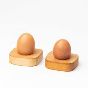 Zwei Eierbecher aus Turnkastenholz mit je einem braunen Ei