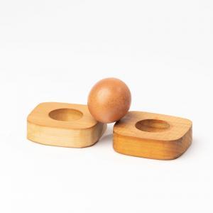 Zwei Ringe aus Turnkastenholz halten ein Ei auf einer Kante