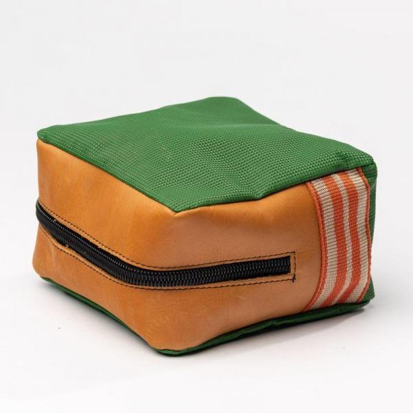 Eine grün und braune quadratische Tasche mit Reißverschluss liegt auf der Seite