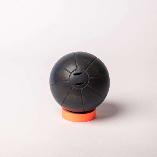 Ein dunkelbrauner Medizinball auf einem orangenen Sockel