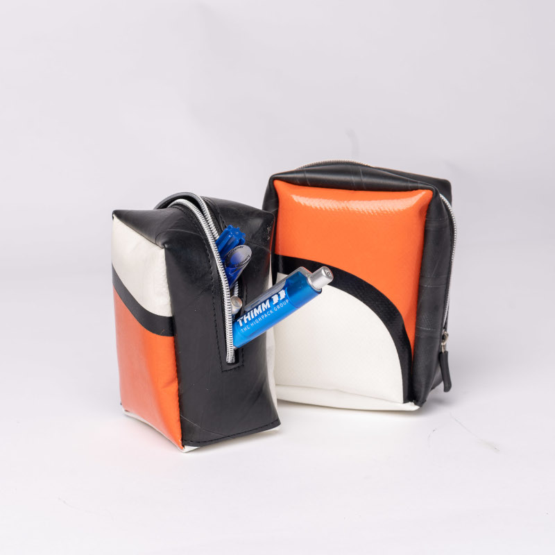 Eine kleine rechteckige Tasche aus orange weiß schwarzen Planen genäht